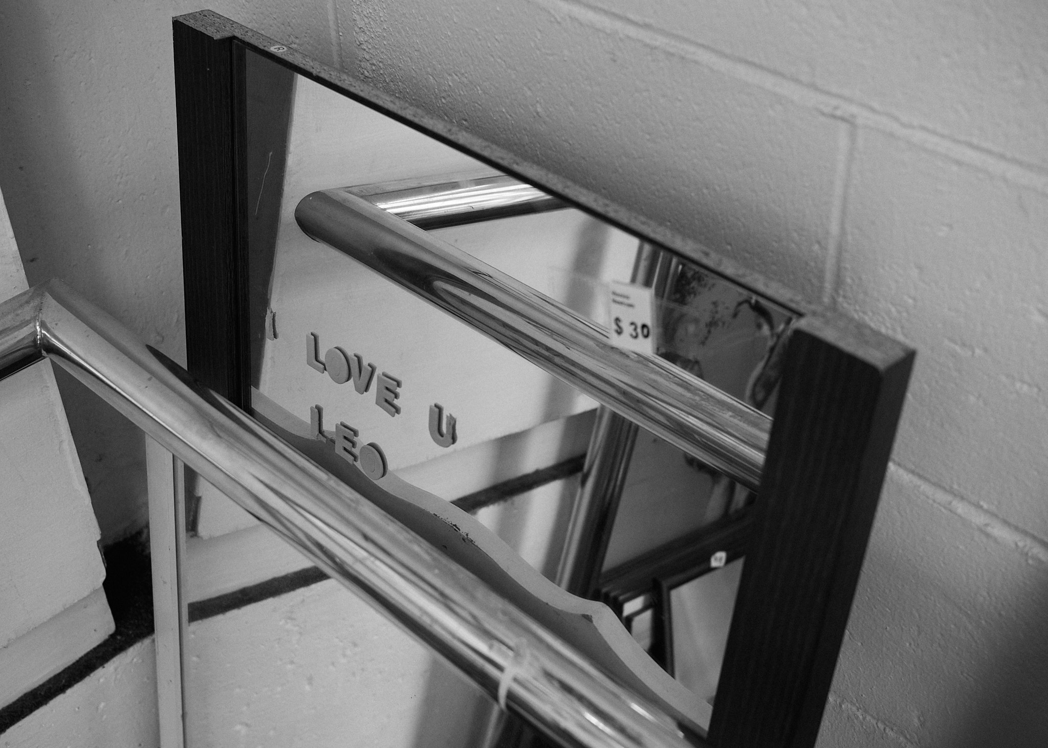 A mirror leans against the wall with the words 'I LOVE U LEO' stuck onto it with foam letters
