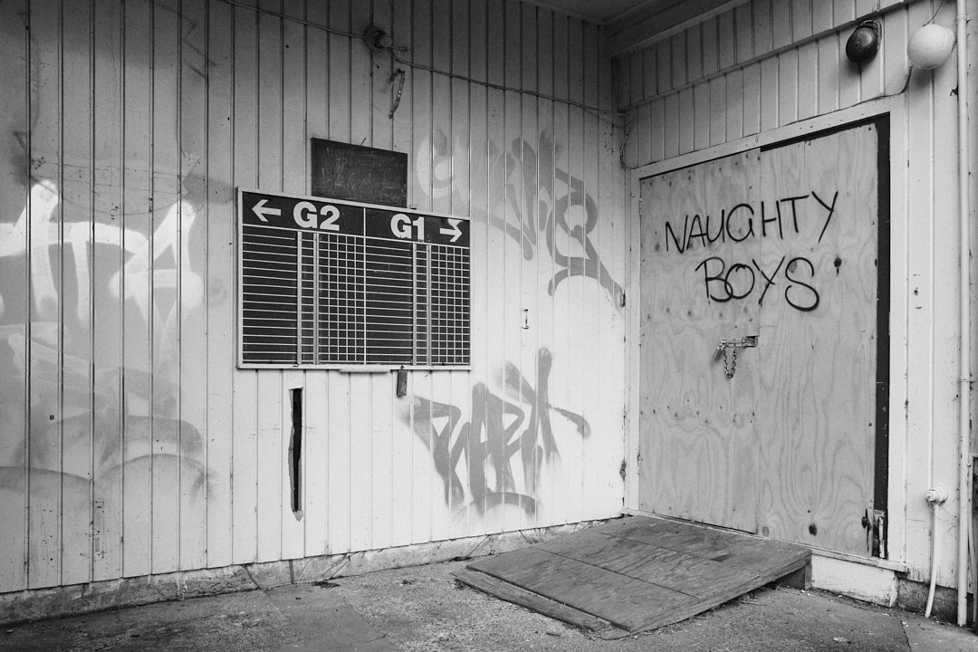 The entrance to a building. 'Naughty Boys' has been tagged on the door.