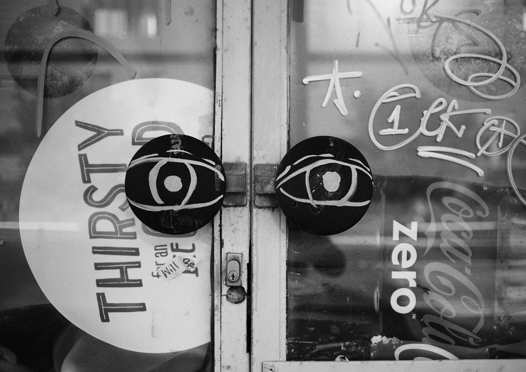 Eyes tagged on the handles of a boarded up door.