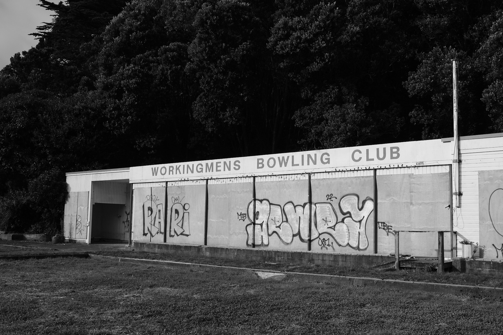 A boarded up building which reads 'WORKINGMENS BOWLING CLUB'.